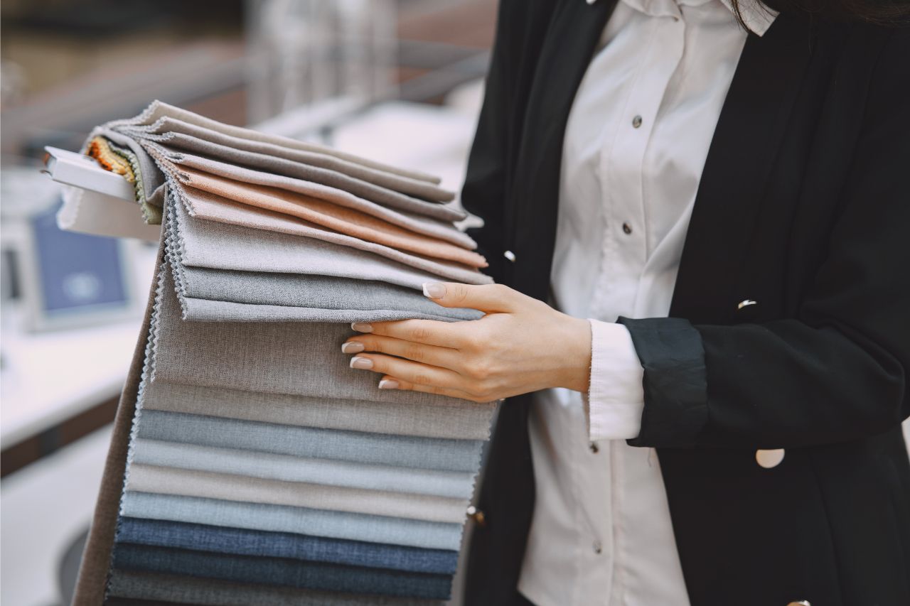 A woman picking out neutral-colored fabrics